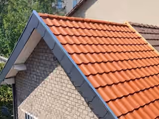 Pan de toiture refait en tuiles rouges, rive grise et pignon en maçonnerie claire, vu de dessus