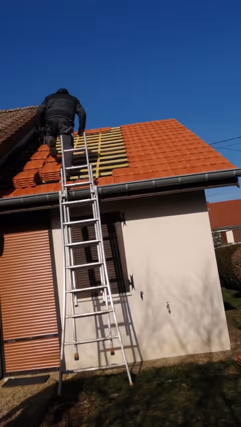 Thibaud Vevert sur un toit, en train de reprendre une couverture en tuiles